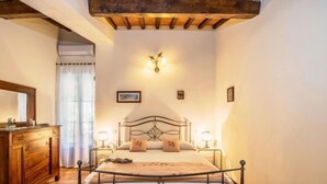 Una camera da letto con un letto con struttura in legno, un comodino con una lampada, una cassettiera e uno specchio grande.