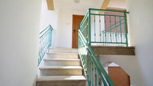 Un escalier avec des rampes vertes menant à une porte en bois.