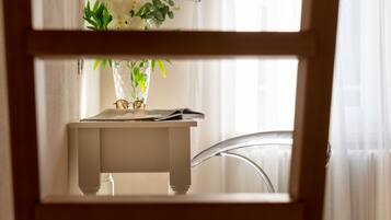A room with a white table, a clear chair, and a window with curtains.