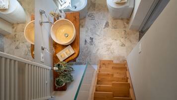 Une salle de bain avec deux lavabos, un meuble-lavabo en bois et une cabine de douche en verre.