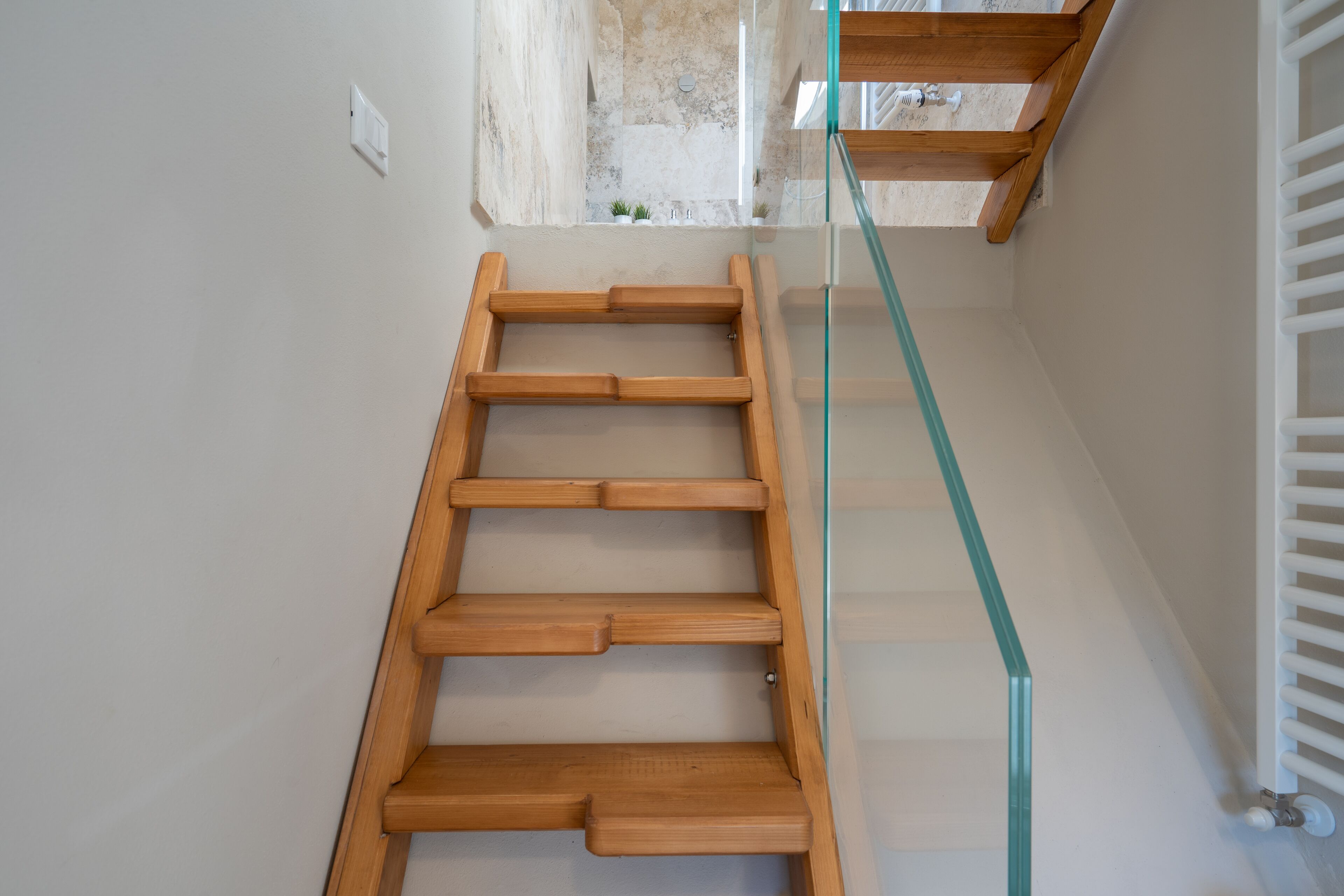 A wooden staircase with glass railings leading to an upper floor.