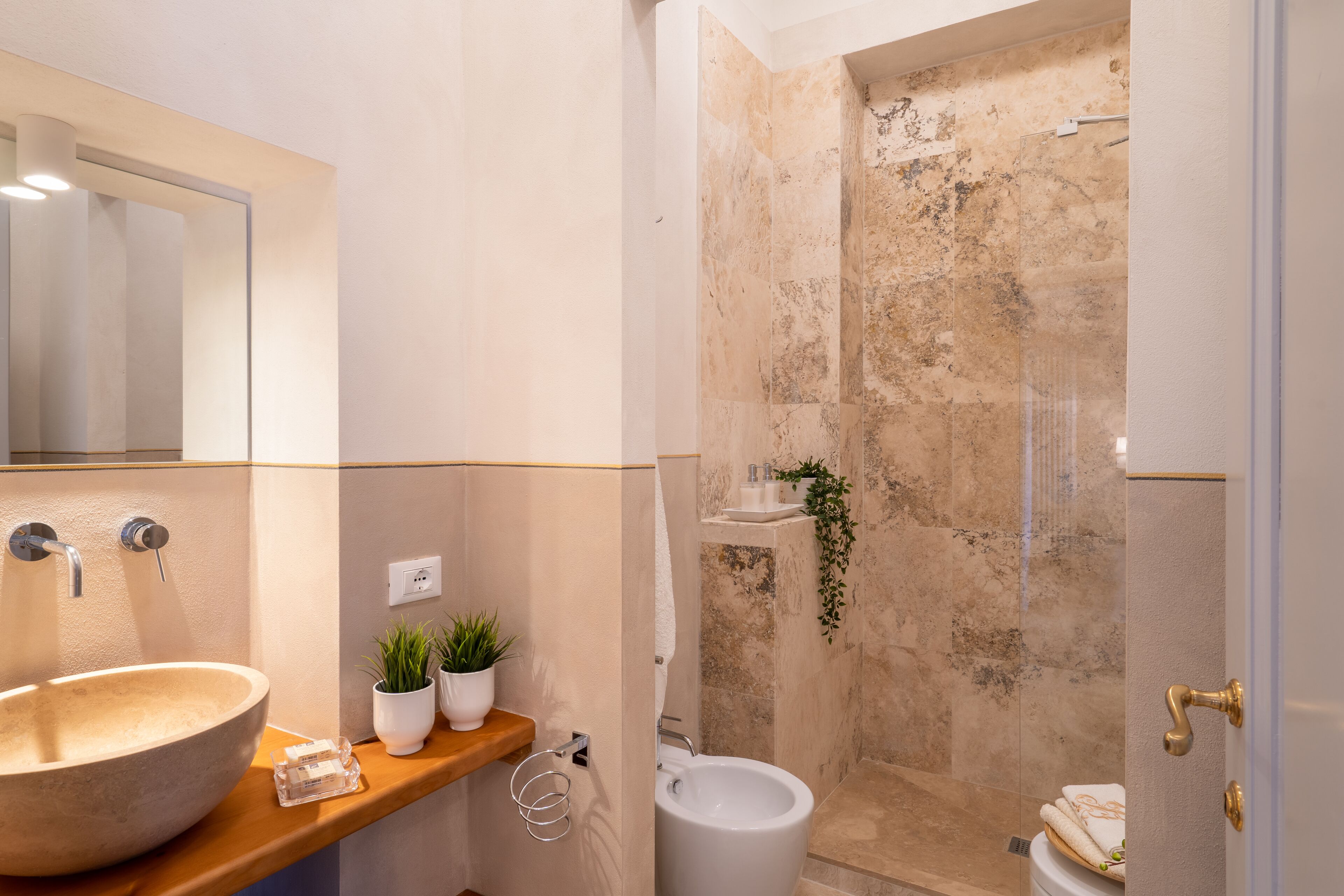 A bathroom with a large sink, a mirror, a toilet, and a shower area.