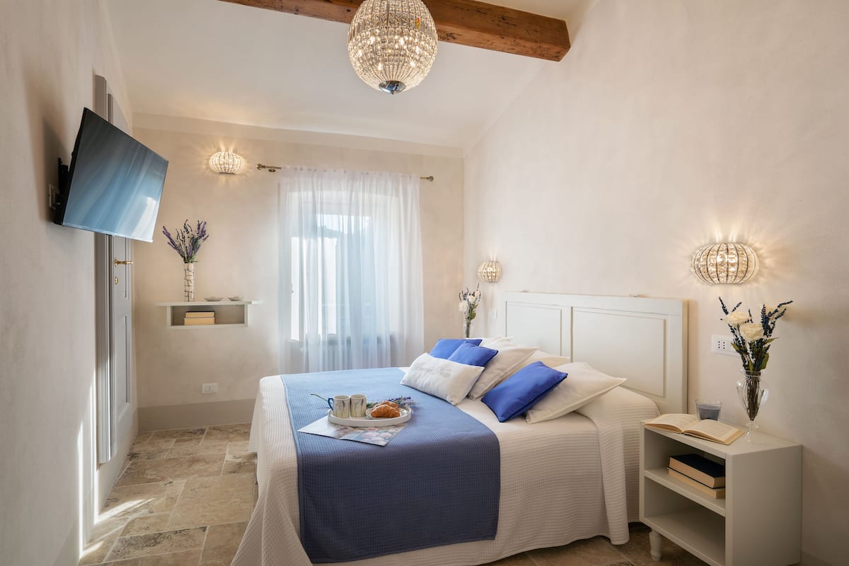 Un dormitorio con cama, mesitas de noche, televisión e iluminación decorativa.