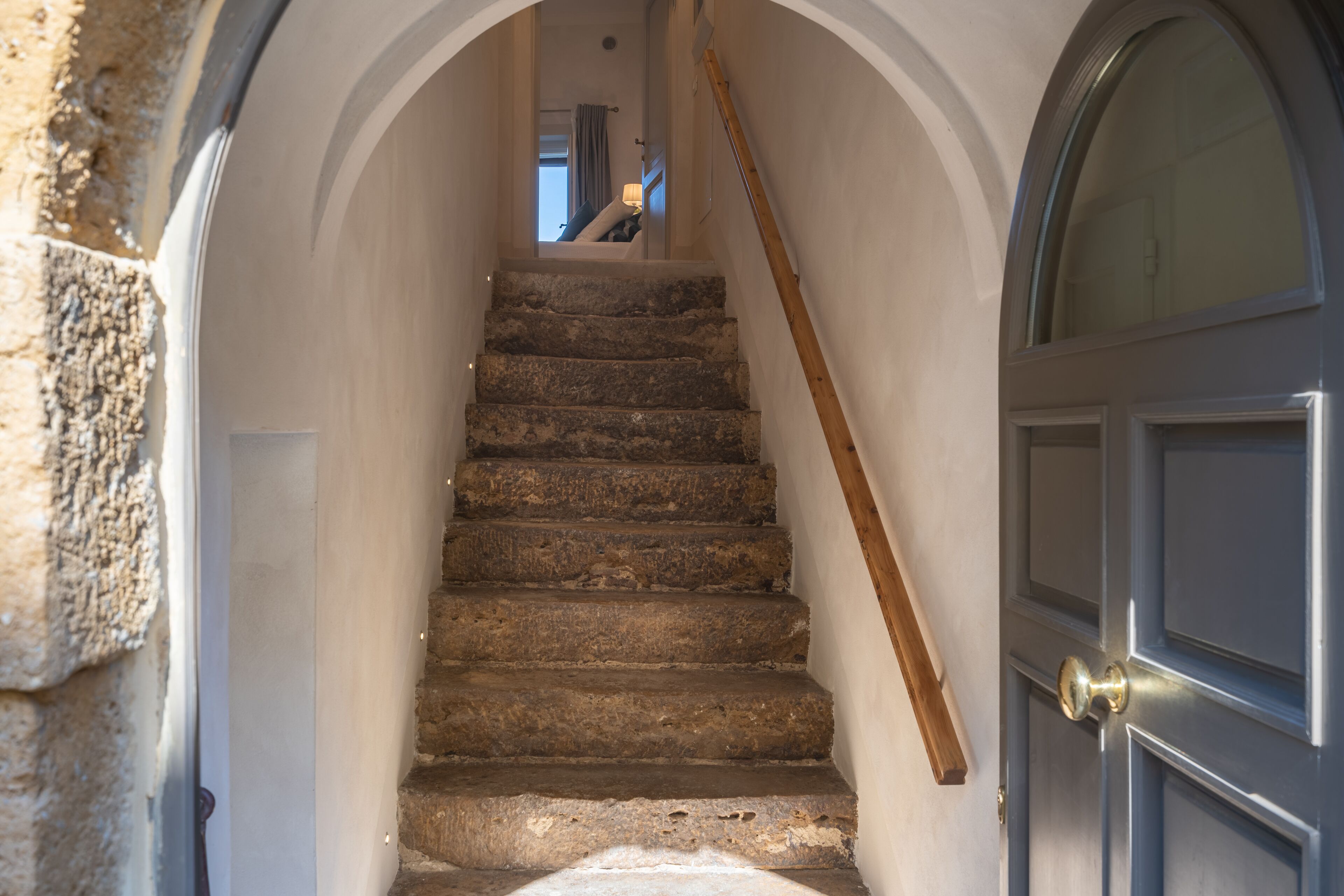 A stone staircase leading to a room with a wooden door and a window.