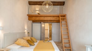 A bedroom with a bunk bed, a ladder, a bedside table, and a bedside lamp.