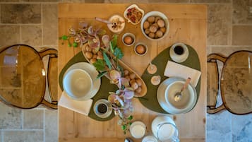 Ein Holztisch mit verschiedenen Frühstücksleckereien, darunter Eier, Nüsse und einer Blumenkomposition.