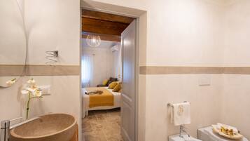 Une salle de bain avec un grand lavabo en pierre, un évier blanc et des toilettes.