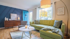 Una sala de estar moderna con un sofá verde, una mesa redonda de centro y una pared azul de acento.
