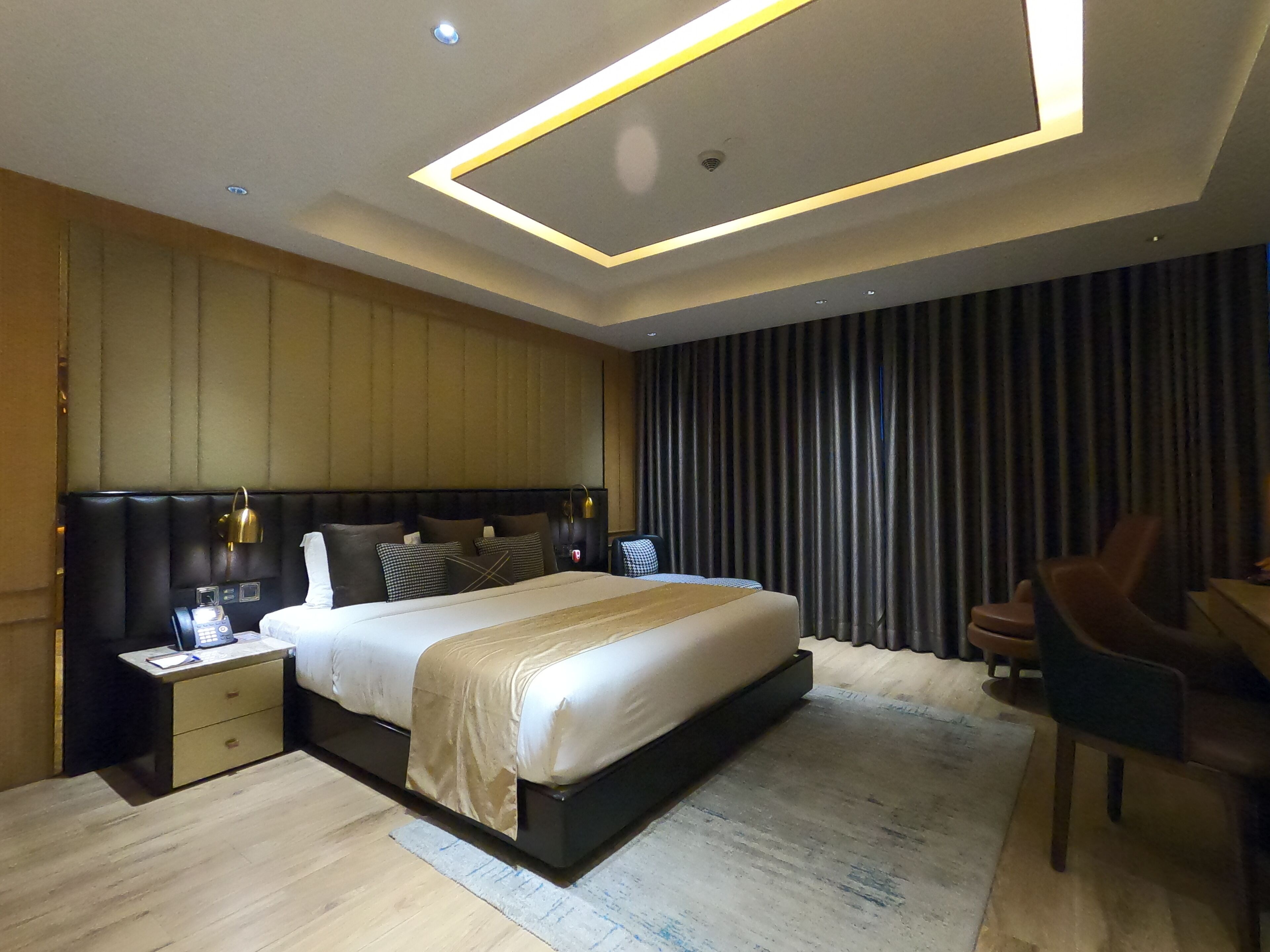 Una habitación de hotel moderna con una cama grande, mesitas de noche, un escritorio y una silla.