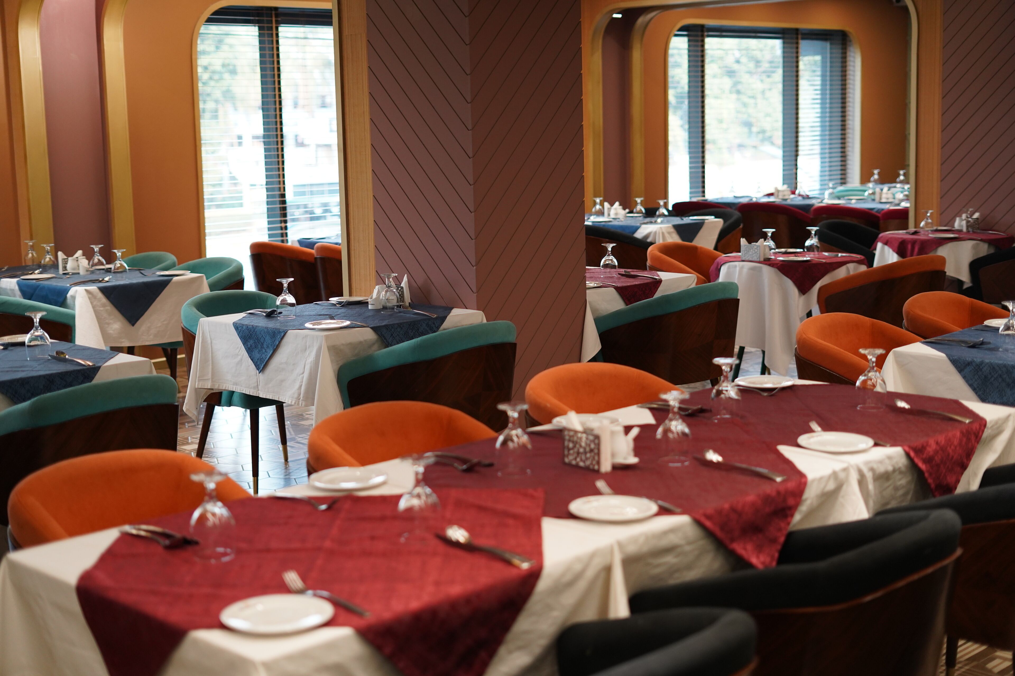 Un espace repas avec des tables dressées pour accueillir plusieurs convives, agrémenté d’une variété de couleurs de nappes et d’un assortiment de styles de chaises.