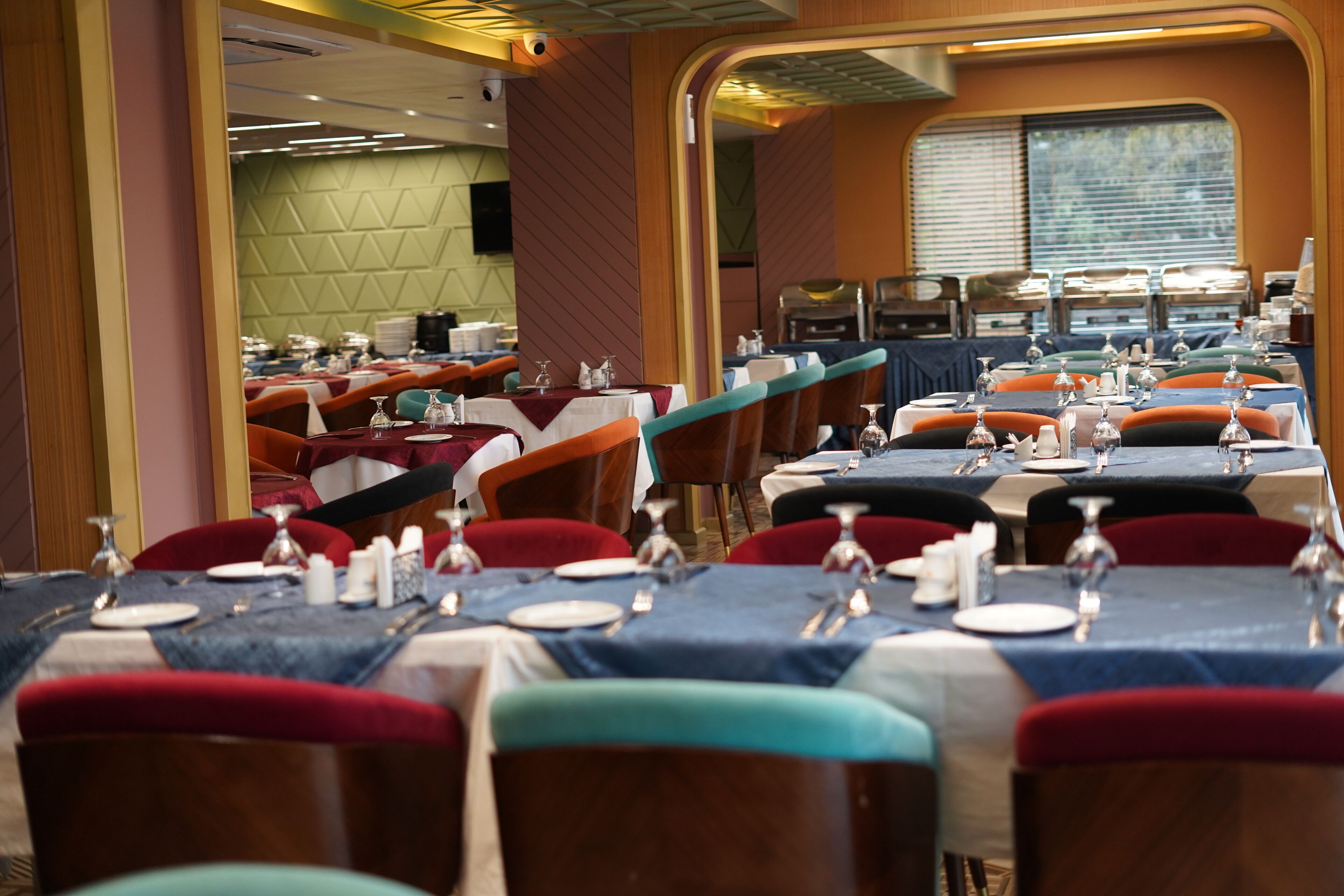 Un restaurante con varias mesas dispuestas para comer, que destaca por la variedad de colores de las sillas y una decoración de estilo moderno.
