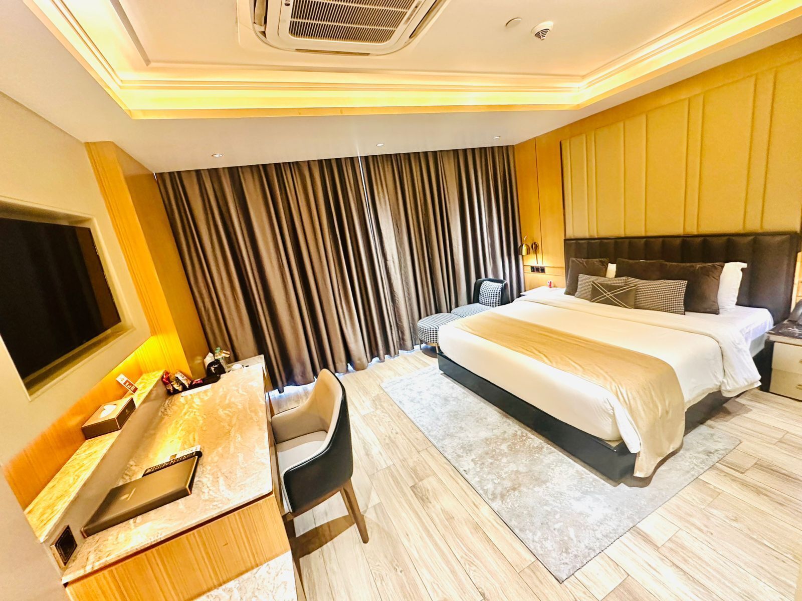 A hotel room with a bed, a desk, a chair, a TV, and a curtain.