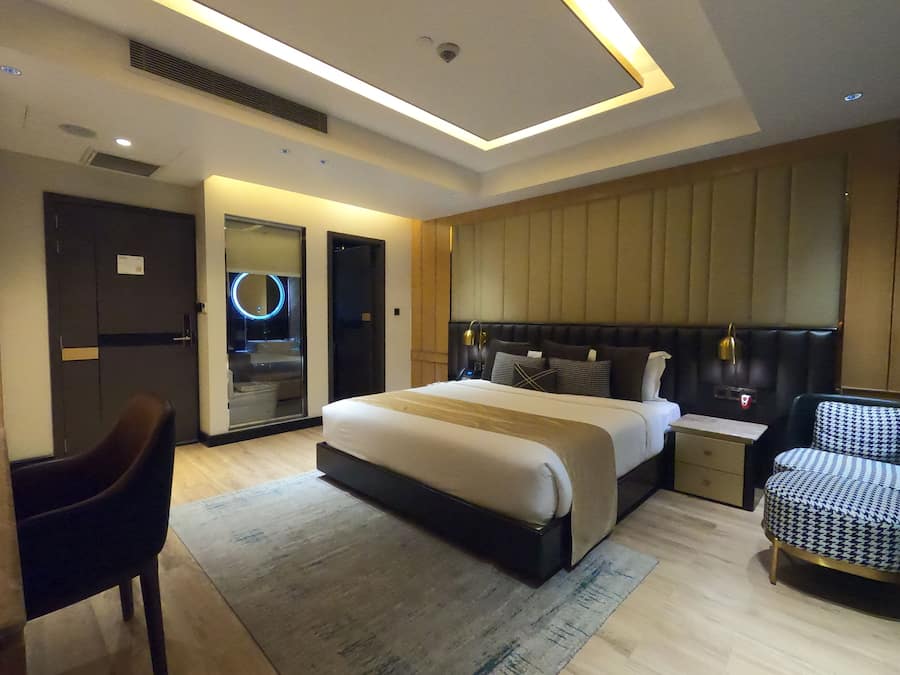 Una habitación de hotel moderna con una cama grande, mesitas de noche, un escritorio y una silla.