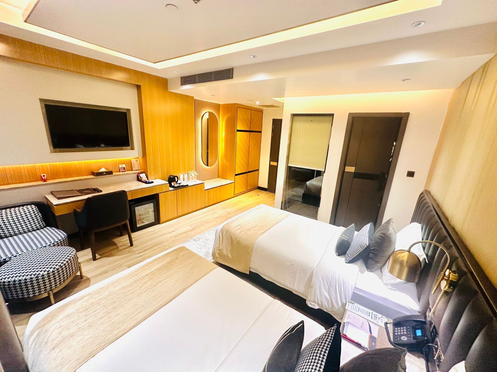 Habitación de hotel con cama, escritorio, silla, televisor y baño.