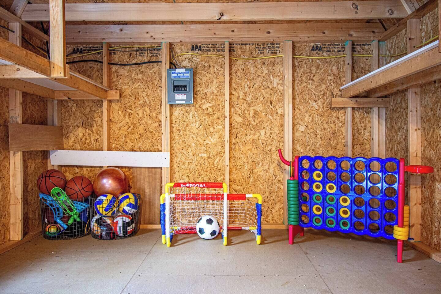 A room with a wooden ceiling, a basketball hoop, a soccer goal, and a toy basketball court.