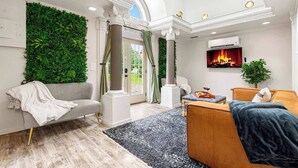 A modern living room with a green wall, a fireplace, and a large window. - Multi-Family Haven! 22ppl, Hot Tub, Golf (Pleasant View)