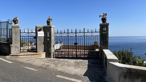A gated entrance with a view of the sea, a plaque, and a car parked inside.