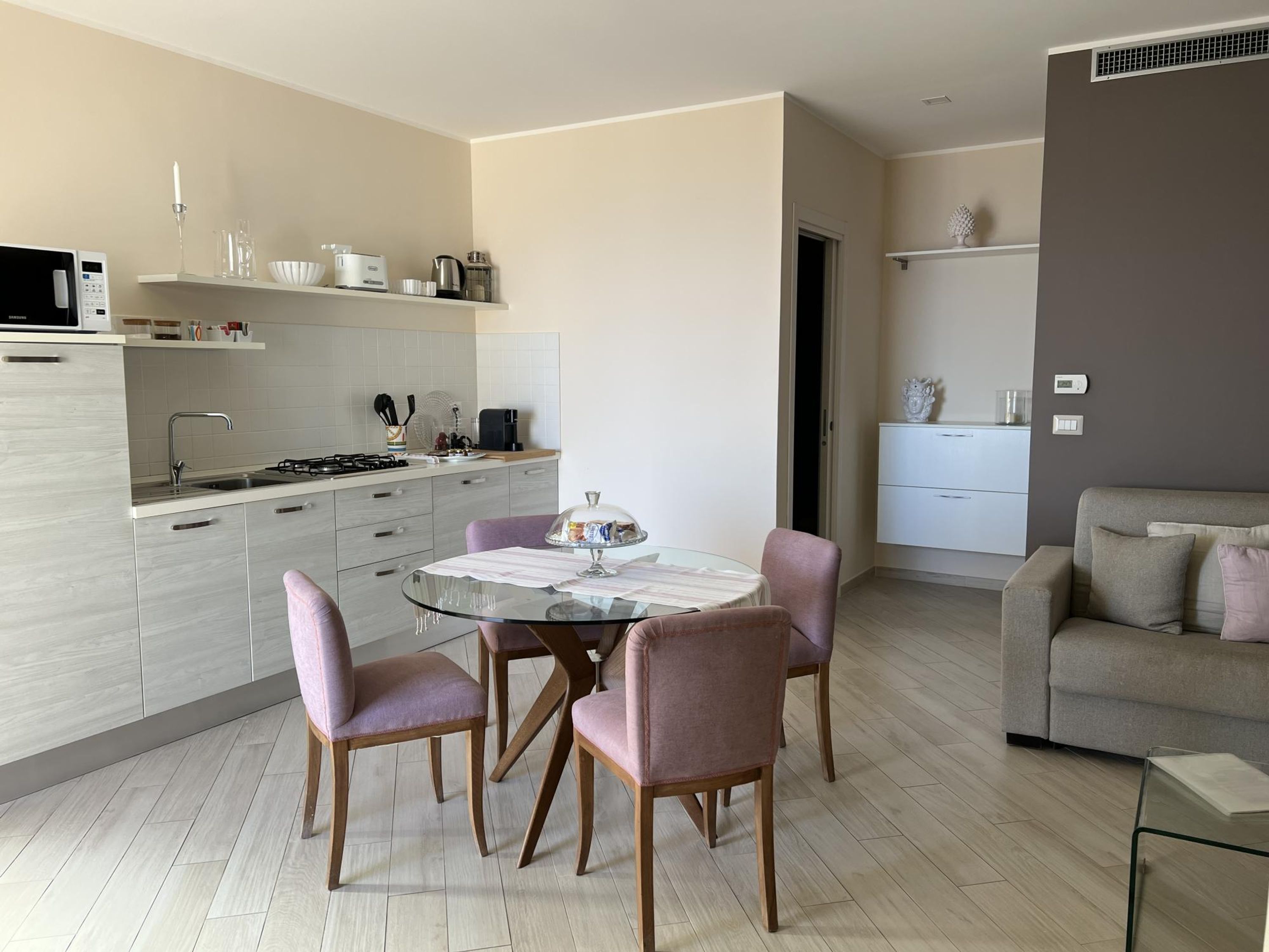 A modern kitchen with a dining area, a sofa, and a small table.
