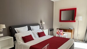 A modern bedroom with a bed, bedside tables, a desk, and a mirror.