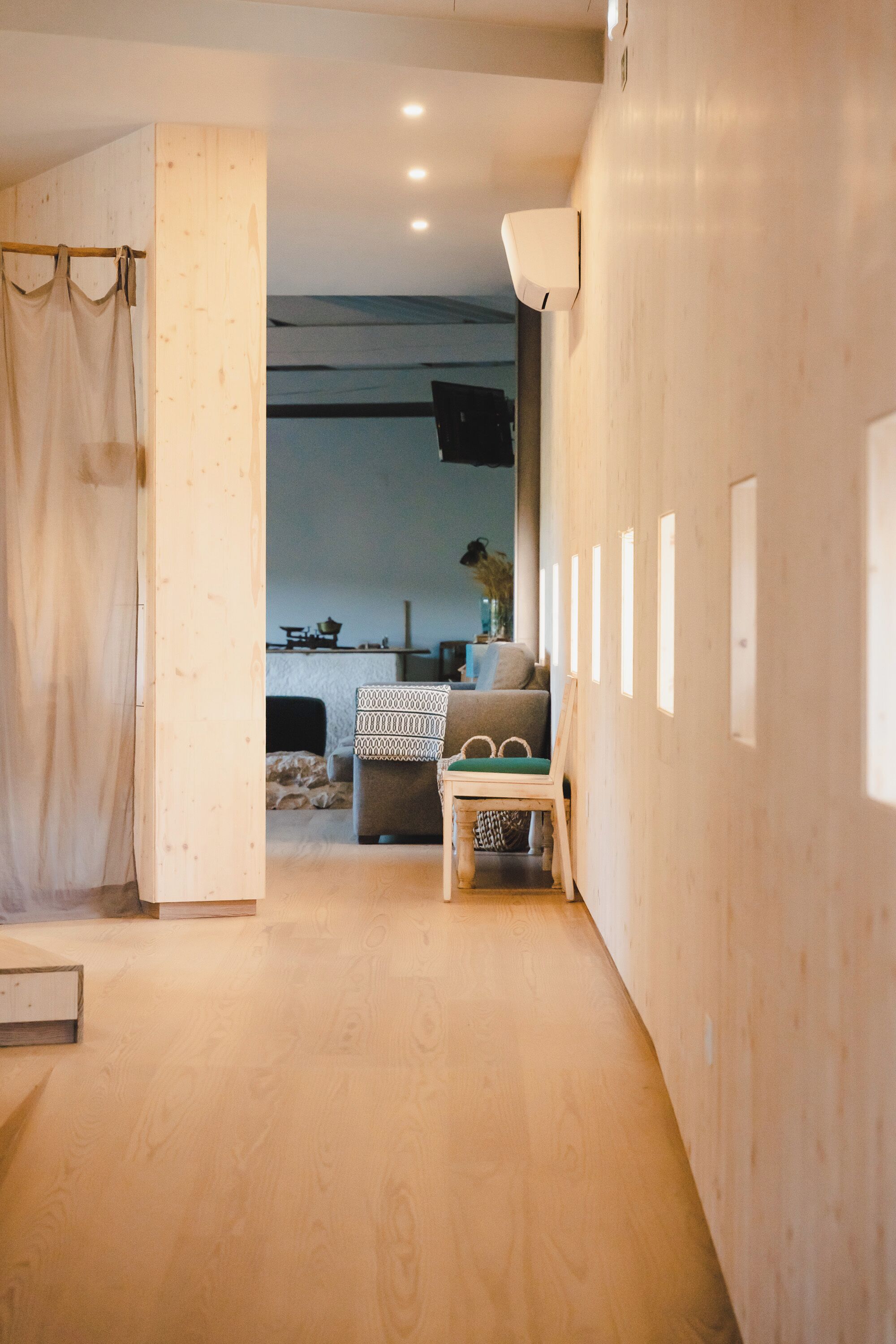Un interior moderno con suelo de madera, un sofá, una mesita y una cortina.