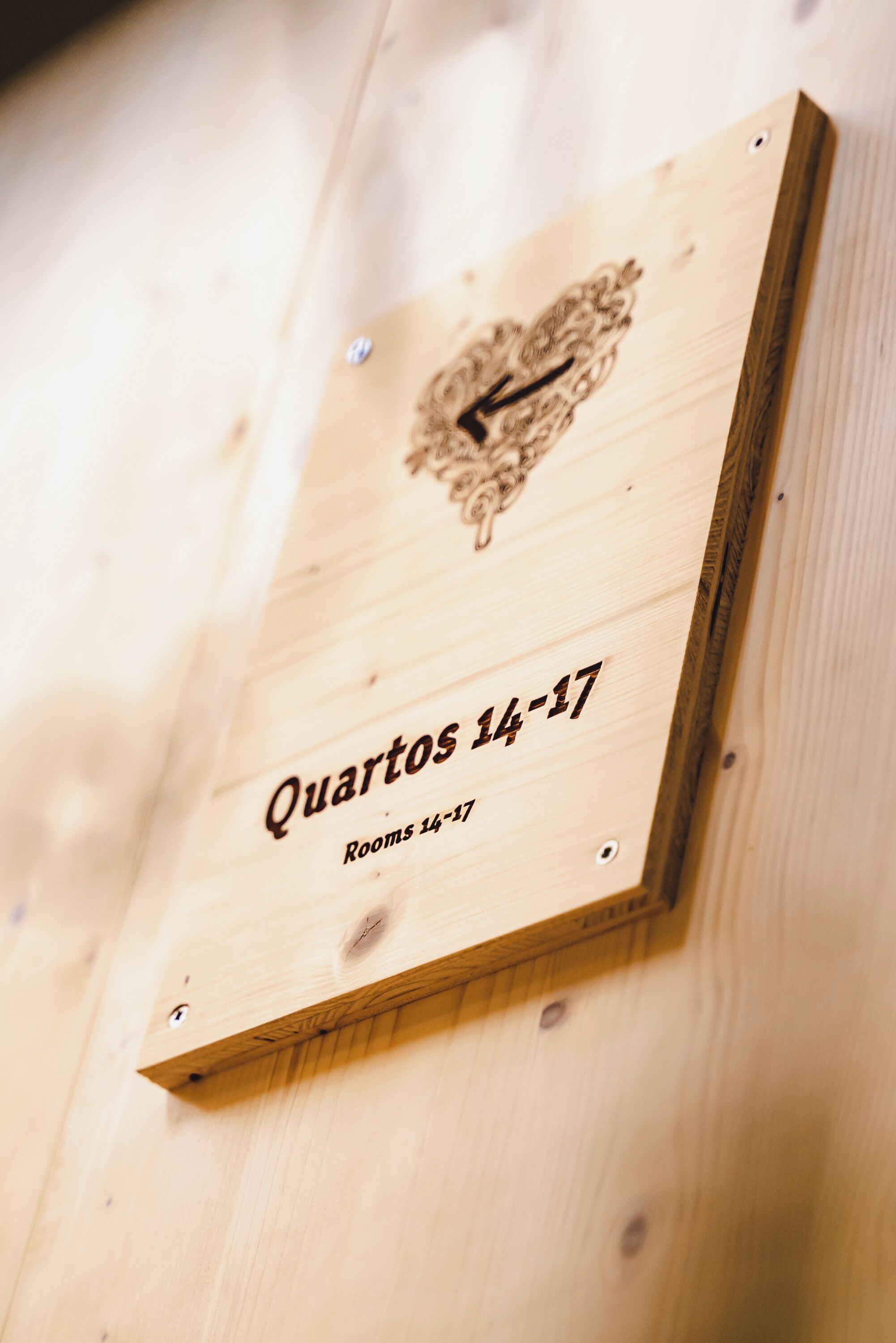 Een houten paneel met de tekst 'Quartos 14-17' en 'Kamer 14-17' ter aanduiding van de kamernummers.