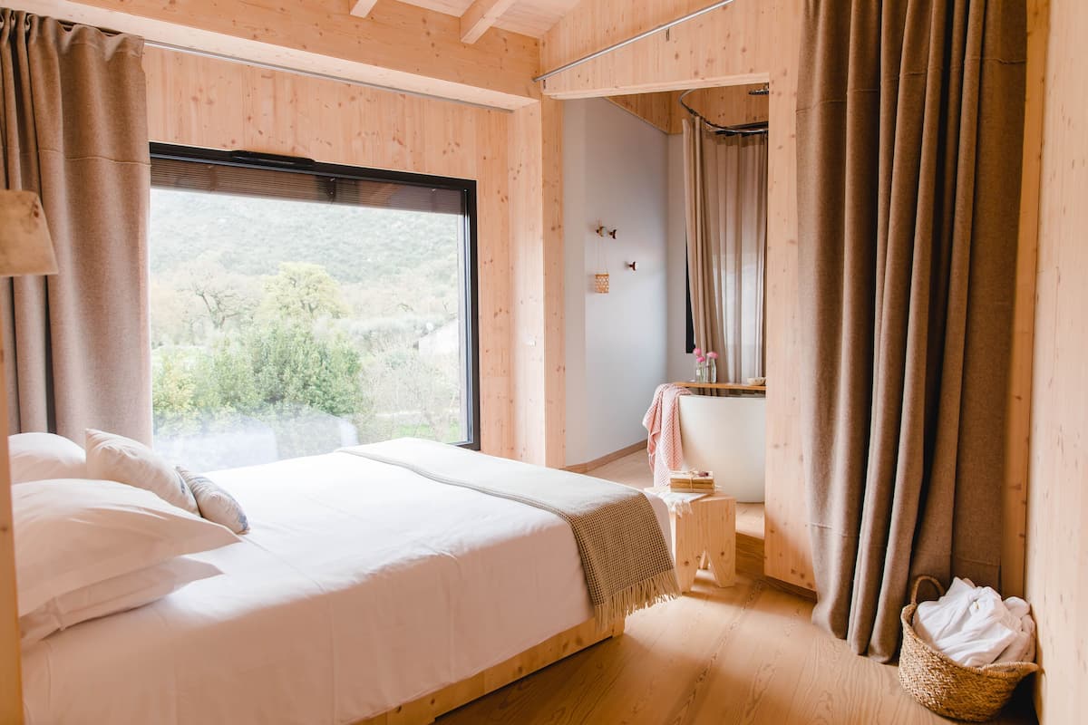 A bedroom with a large bed, a window, and a wooden floor.