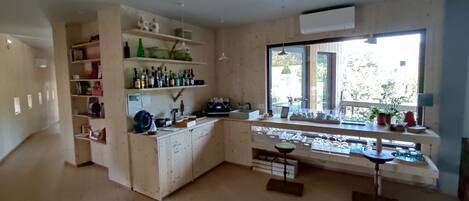 A spacious kitchen with wooden cabinets, a built-in wine rack, and a large window providing natural light.
