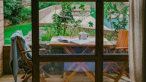 Une pièce dotée d’une grande fenêtre, d’un plancher en bois, d’une table avec des chaises et d’un lit.