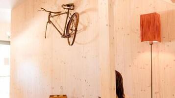 Ein Zimmer mit einer Holztreppe, einem hängenden Fahrrad, einer Stehlampe und einer Person, die auf einem Sitzsack sitzt.