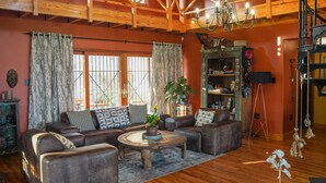A cozy living room with a wooden ceiling, a round coffee table, and a sofa set. - Ti Melen Boutique Guesthouse l Ondili (Windhoek)