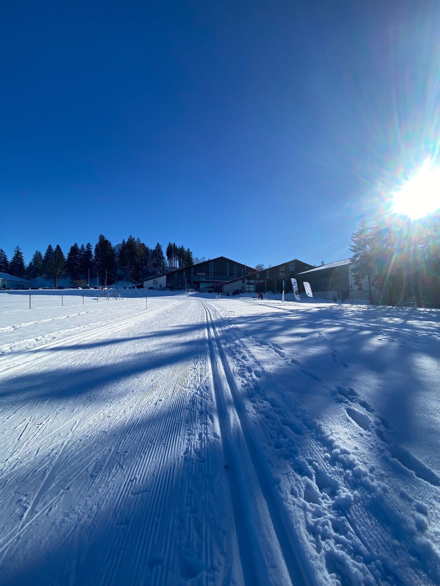 Une piste de ski enneigée, avec un hôtel en arrière-plan.