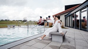 Zona de piscina con banco, piscina y edificio con amplios ventanales.