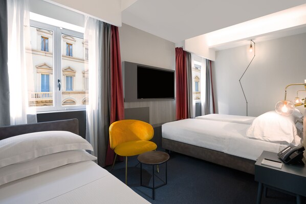 A hotel room with two beds, a TV, a desk with a lamp, and a chair. - IQ Hotel Firenze (Florence)