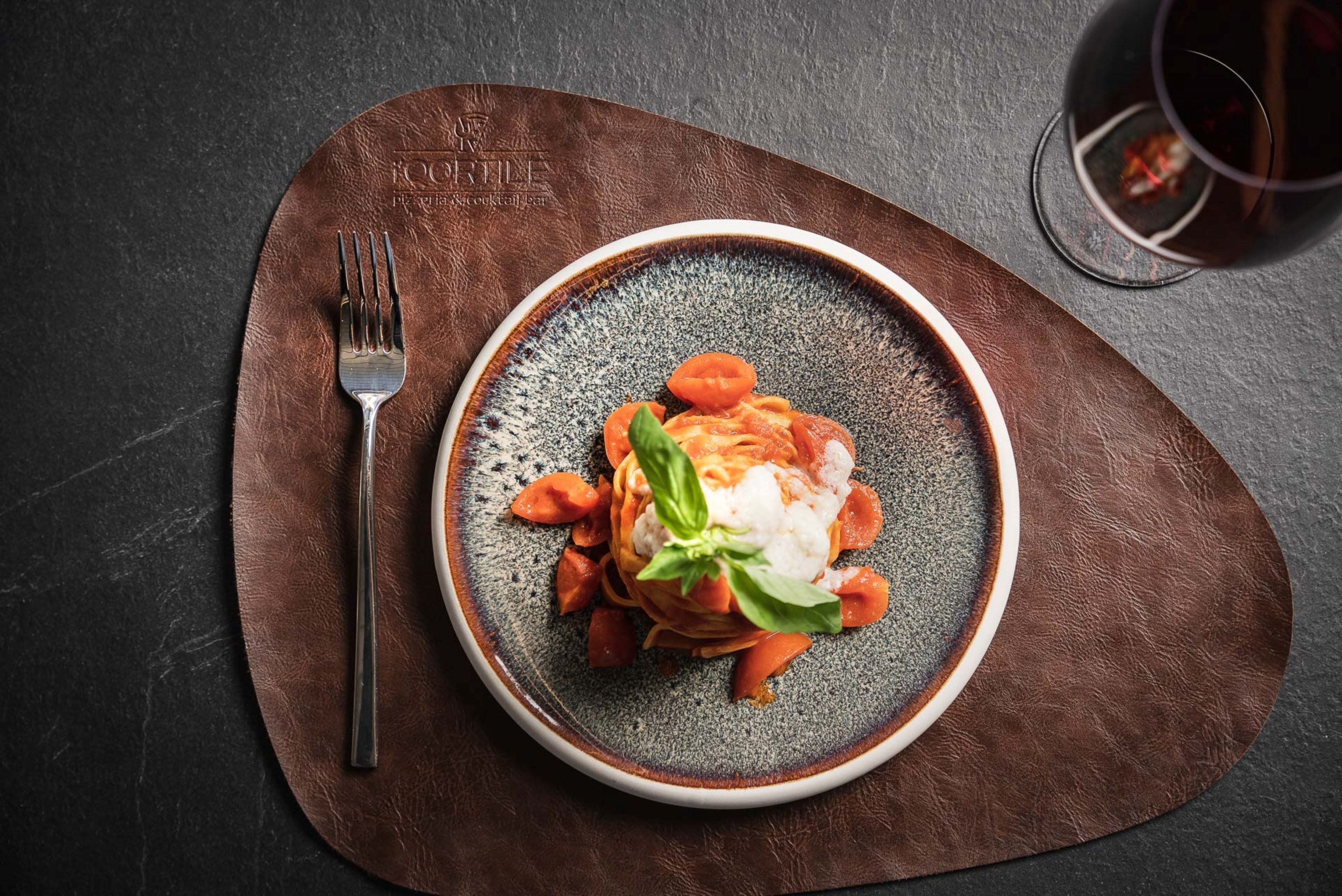 Un plato de pasta con un tenedor sobre un camino de mesa marrón.