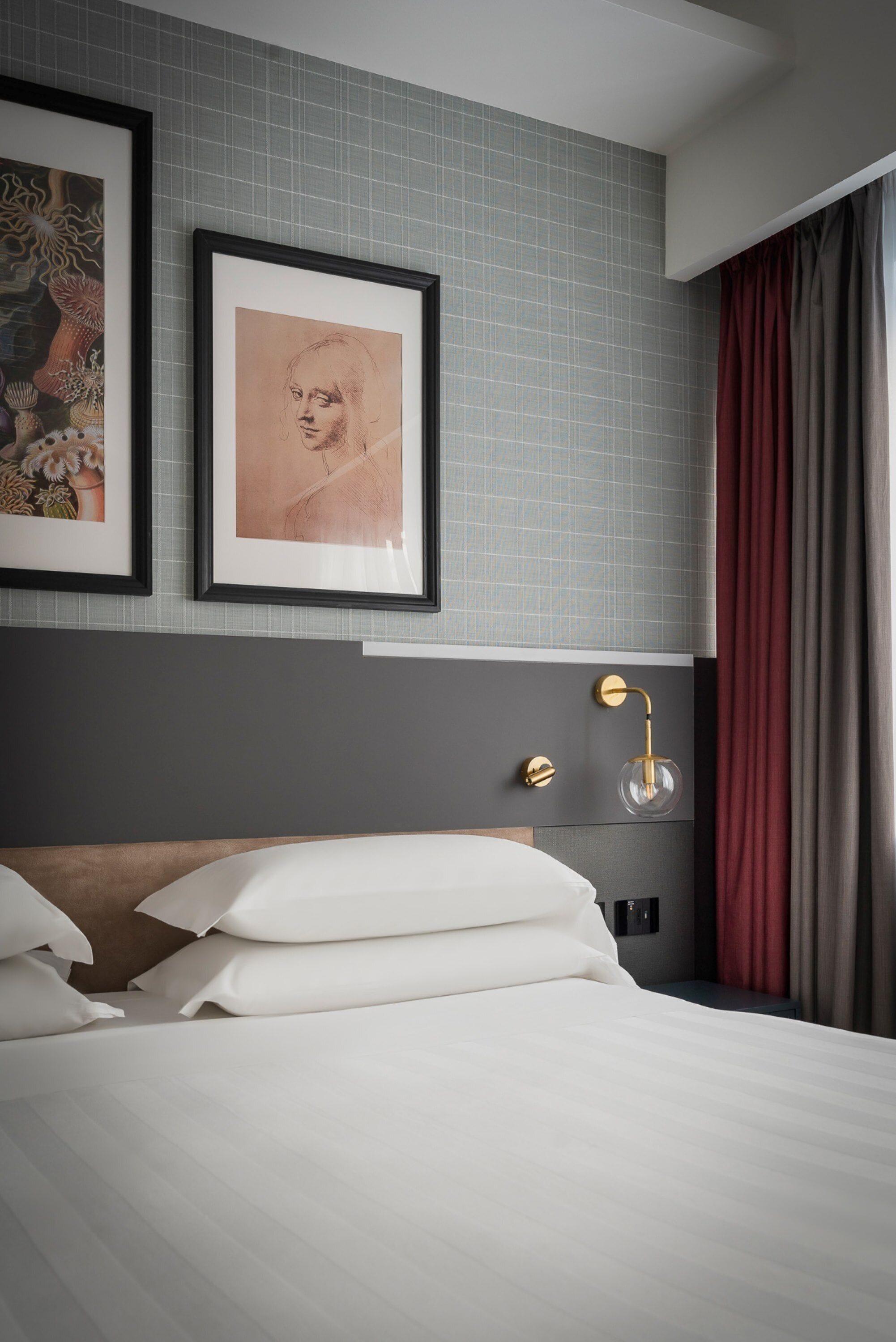 A neatly made bed with white linens, a headboard with a gold accent, and a framed artwork above it.