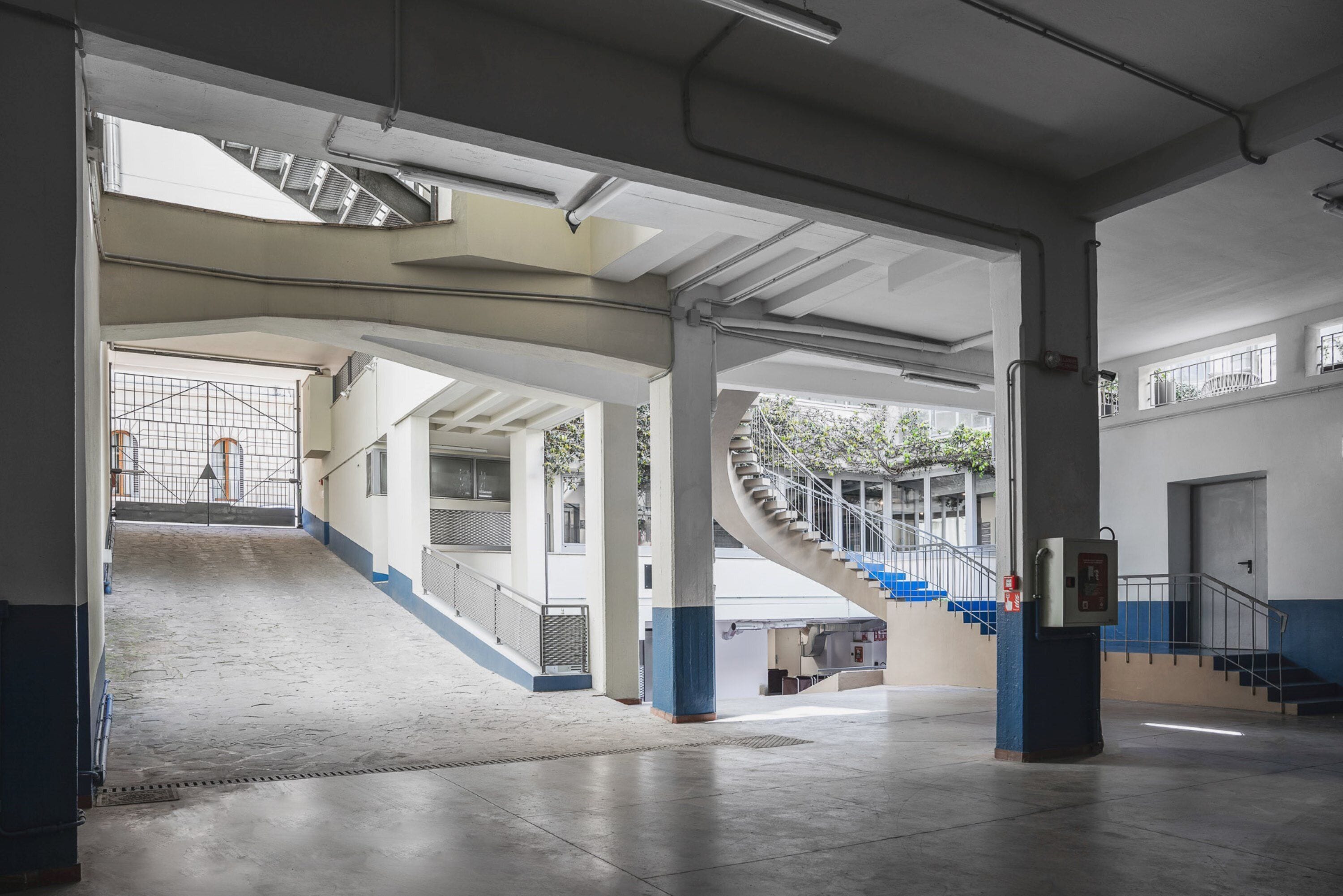 A spacious indoor area with a central staircase, large pillars, and a view of an outdoor area with stairs.
