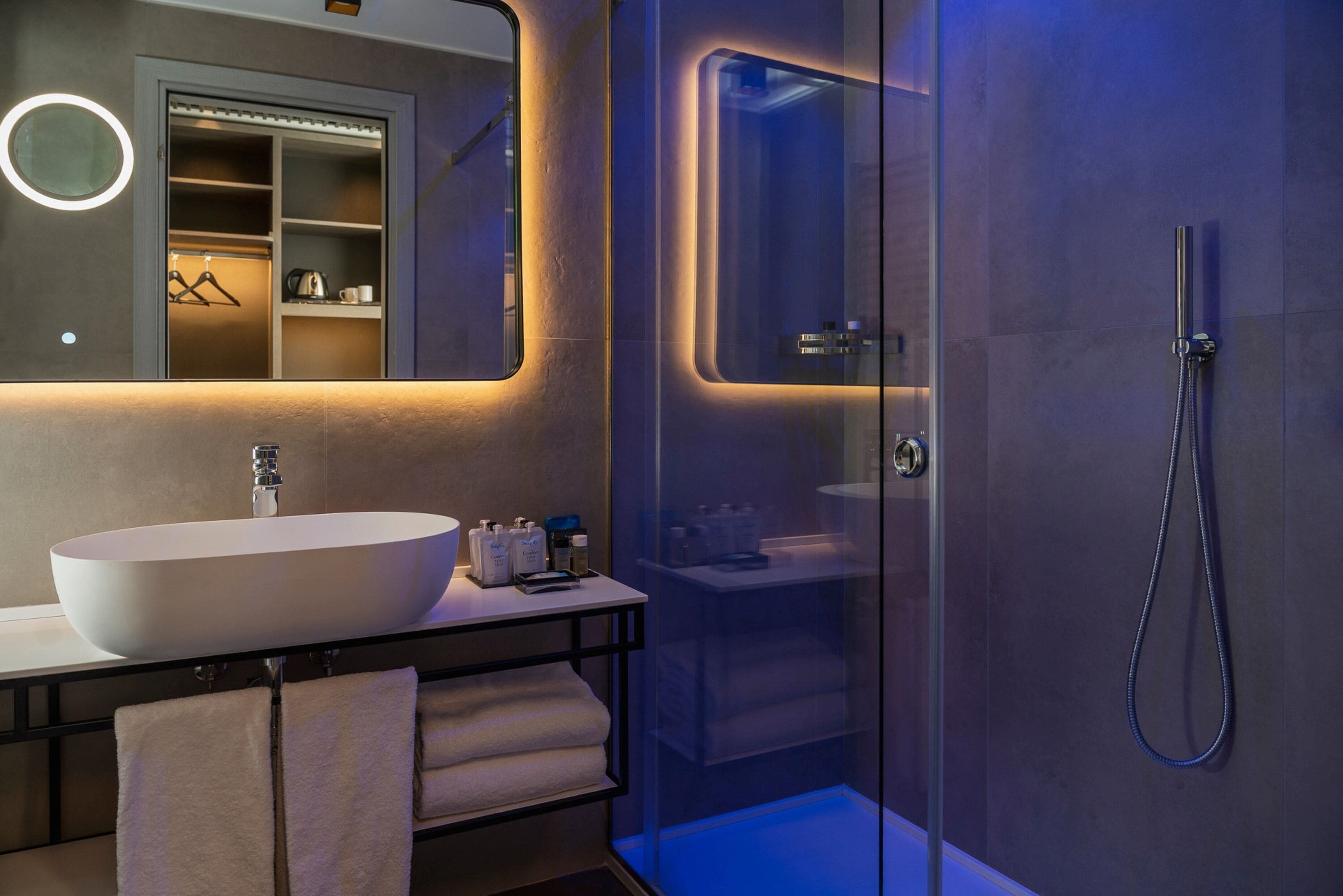 Un baño moderno con un lavamanos ovalado grande, cabina de ducha de vidrio y ducha a ras de suelo.