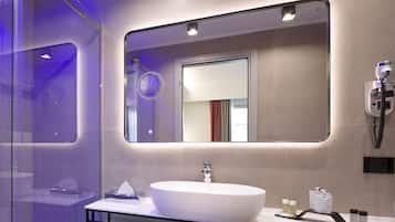 Un baño moderno con un lavamanos ovalado grande, un espejo y una cabina de ducha de vidrio.