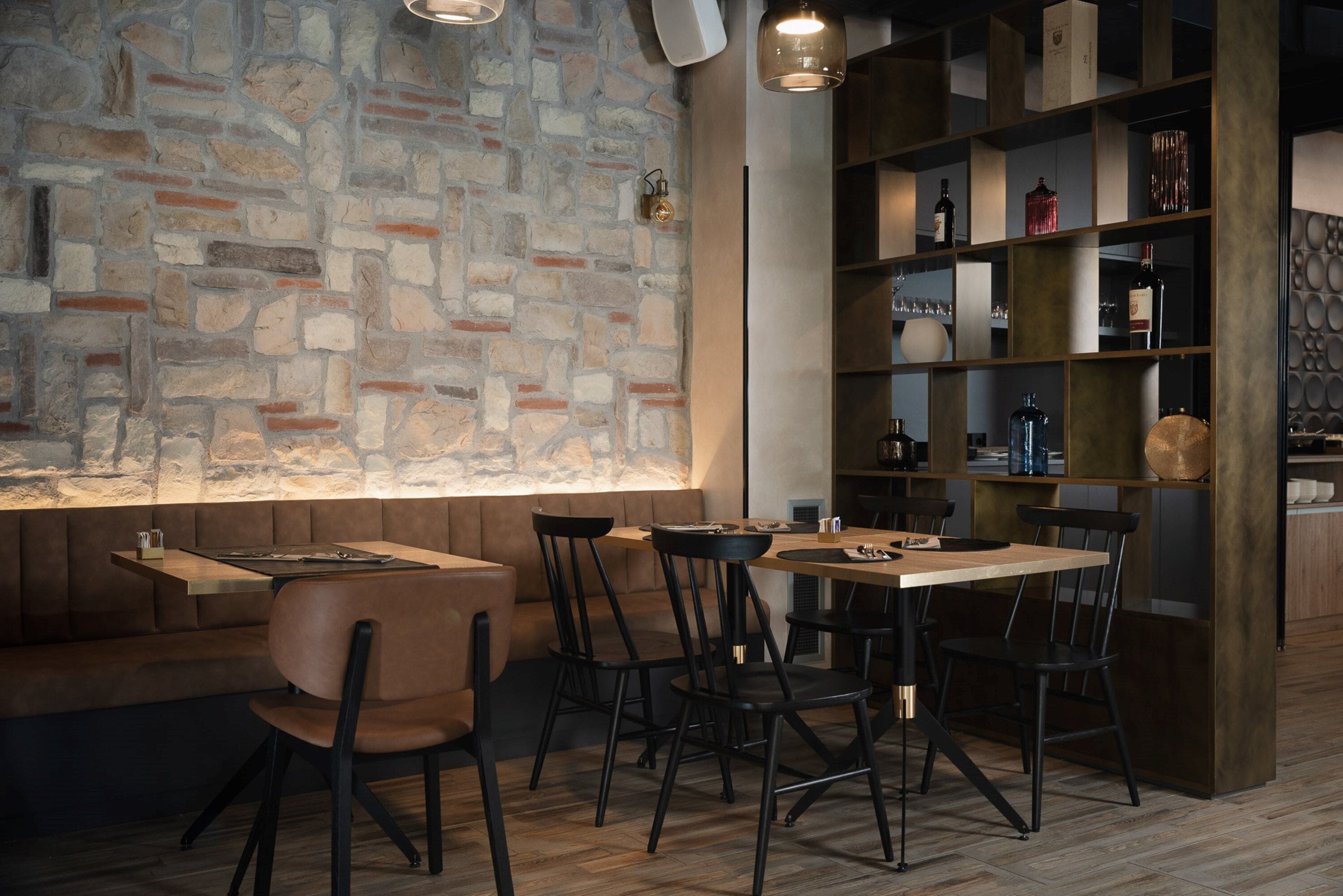 Un restaurante con pared de piedra, mesas de madera y sillas negras.