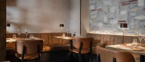 A restaurant interior with booth seating, tables, and a stone wall.