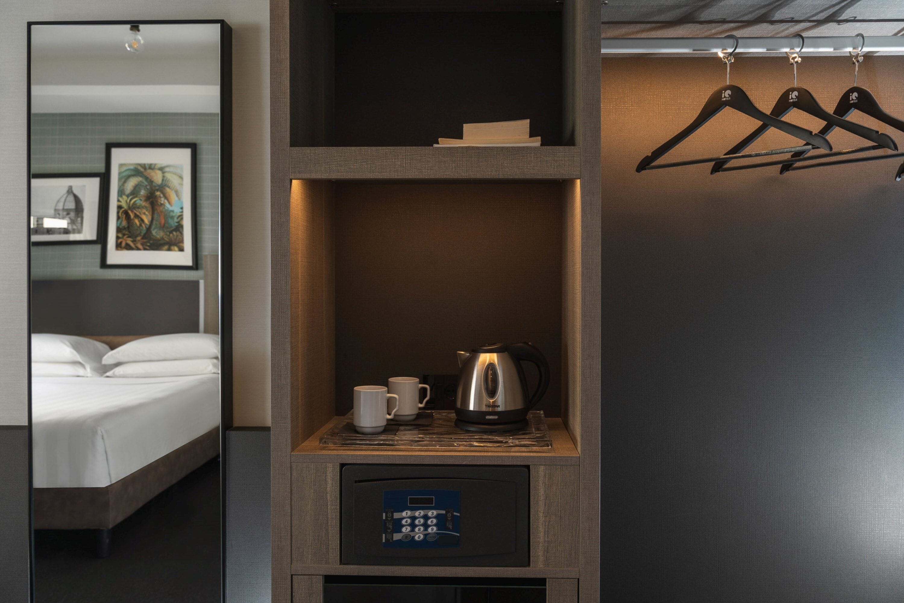 Ein Hotelzimmer mit einem Bett, einer Kaffeemaschine, einer Tasse und einer Bedienkonsole.