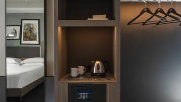 Ein Hotelzimmer mit einem Bett, einer Kaffeemaschine, einer Tasse und einer Bedienkonsole.