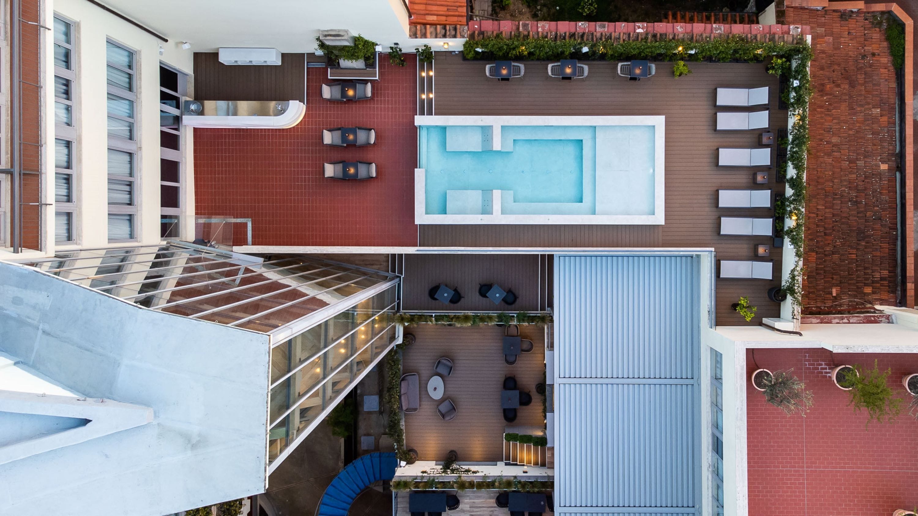 A rooftop terrace with a swimming pool, outdoor seating, and a glass-enclosed area.