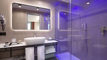 Un bagno moderno con uno specchio grande, un lavabo bianco e una cabina doccia in vetro.