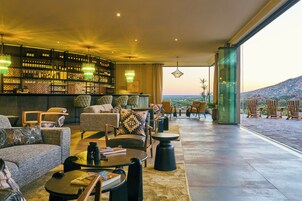 Un vaste espace salon doté de sièges confortables, un bar proposant un large choix de boissons, et une grande fenêtre offrant une vue sur le paysage.