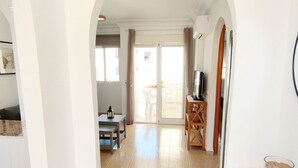 Ein Flur mit Essbereich, einem Fernseher auf einem Holzboden und einer Glasschiebetür zu einem Außenbereich.