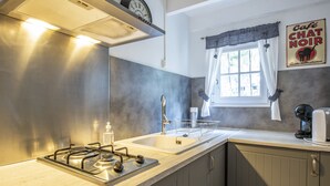 Eine moderne Küche mit Gaskochfeld, doppeltem Spülbecken und einem Fenster mit Vorhängen.