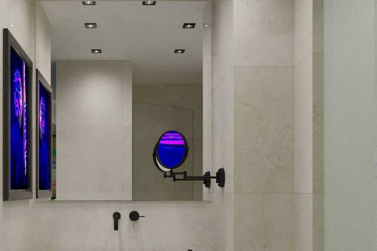 Ein modernes Badezimmer mit einem weißen Waschbecken, zwei Seifenflaschen, einem runden Spiegel und einem Holzboden mit Handtüchern.