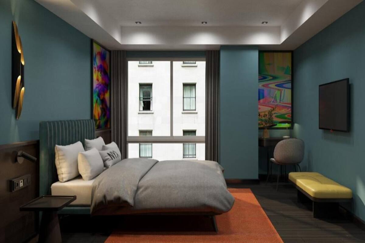 Ein modernes Hotelzimmer mit Bett, Schreibtisch, Stuhl und Blick auf ein Gebäude durch ein Fenster.