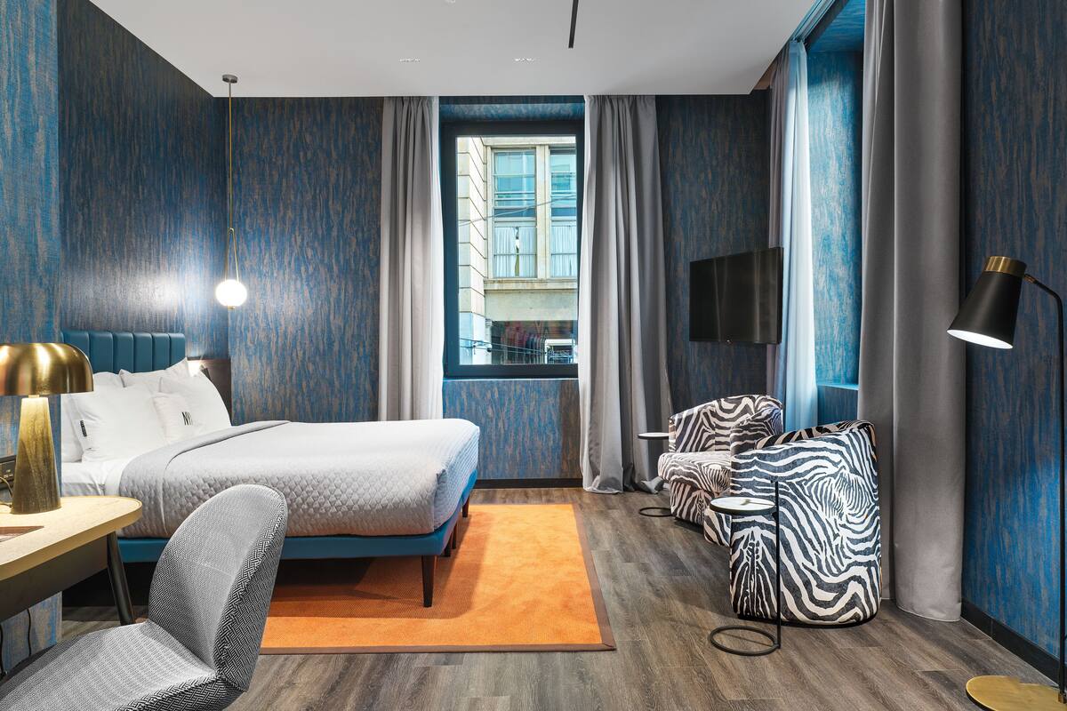 Ein modernes Hotelzimmer mit einem großen Bett, einem Schreibtisch, einem Stuhl, einer Couch und einem Fernseher.